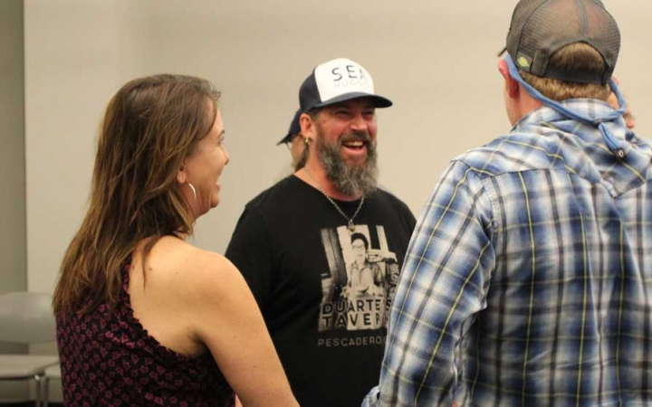 A group of adults smile at a family seminar after an outward bound course